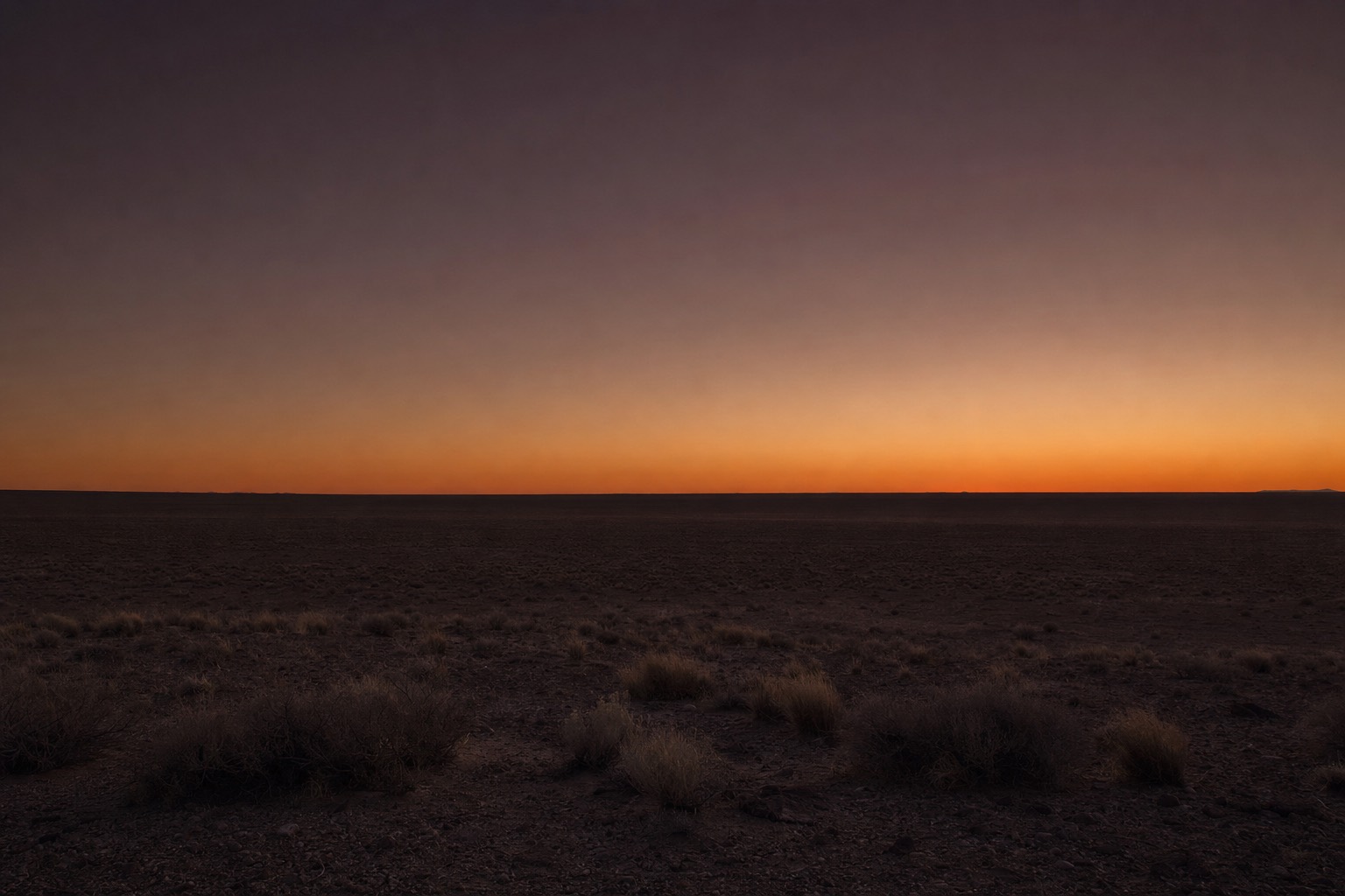 A calm, level horizon at dusk under a quiet sky