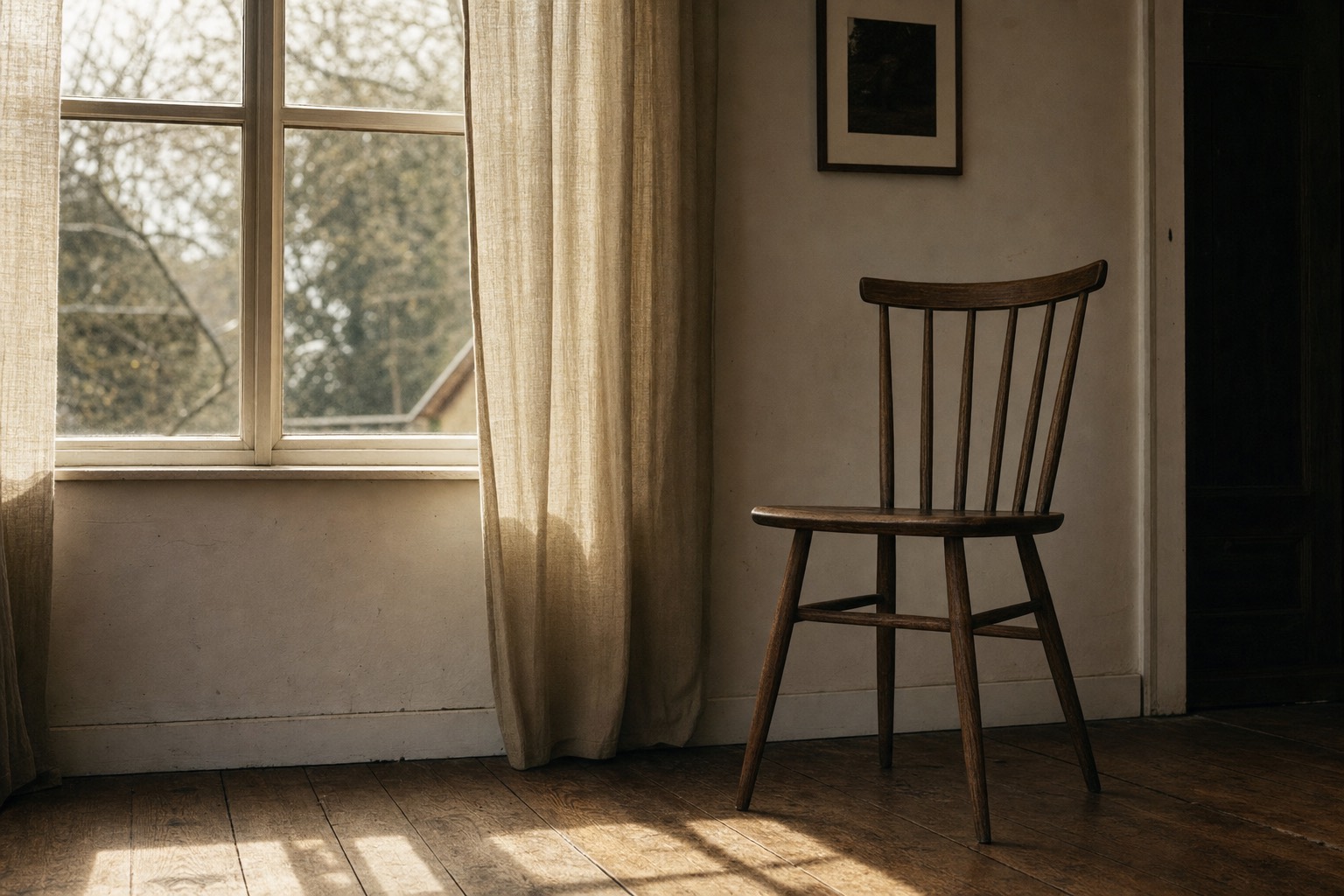 An empty chair beside a window in warm, low evening light